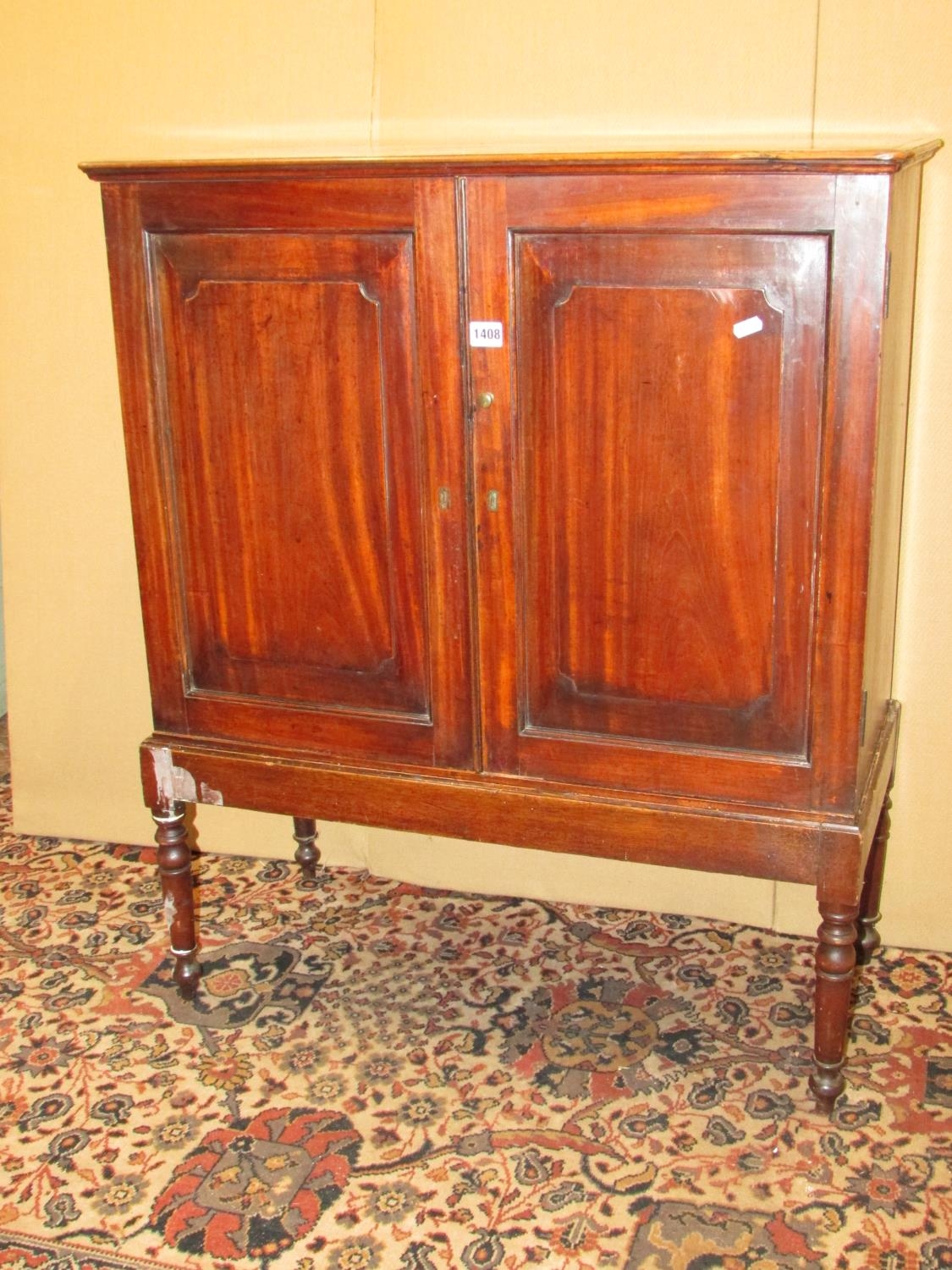 A Georgian satin wood cupboard enclosed by two fielded panelled doors, raised on an open