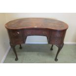 A walnut framed kneehole kidney shaped writing desk fitted with five drawers on pad feet with