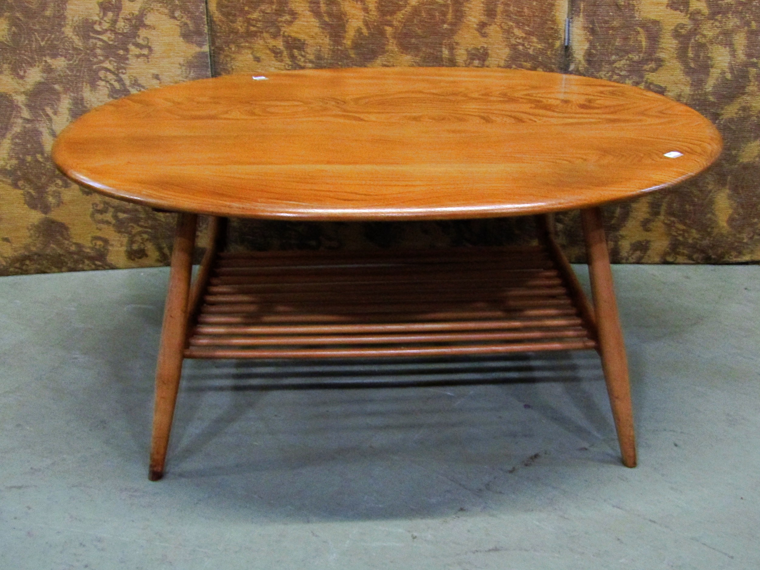 An Ercol occasional table of oval form, on turned supports with under gallery, with well figured elm