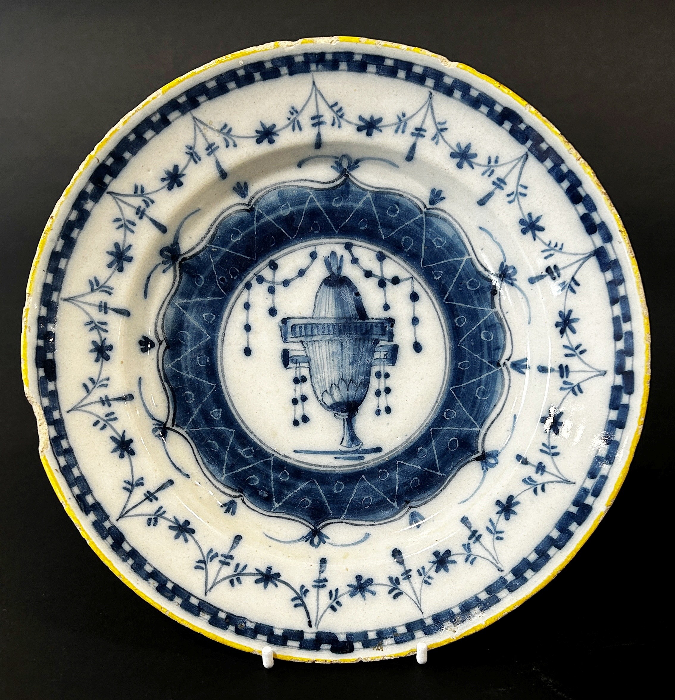 An 18th century tin glazed plate in a blue and white colourway, the central urn within further - Image 2 of 3