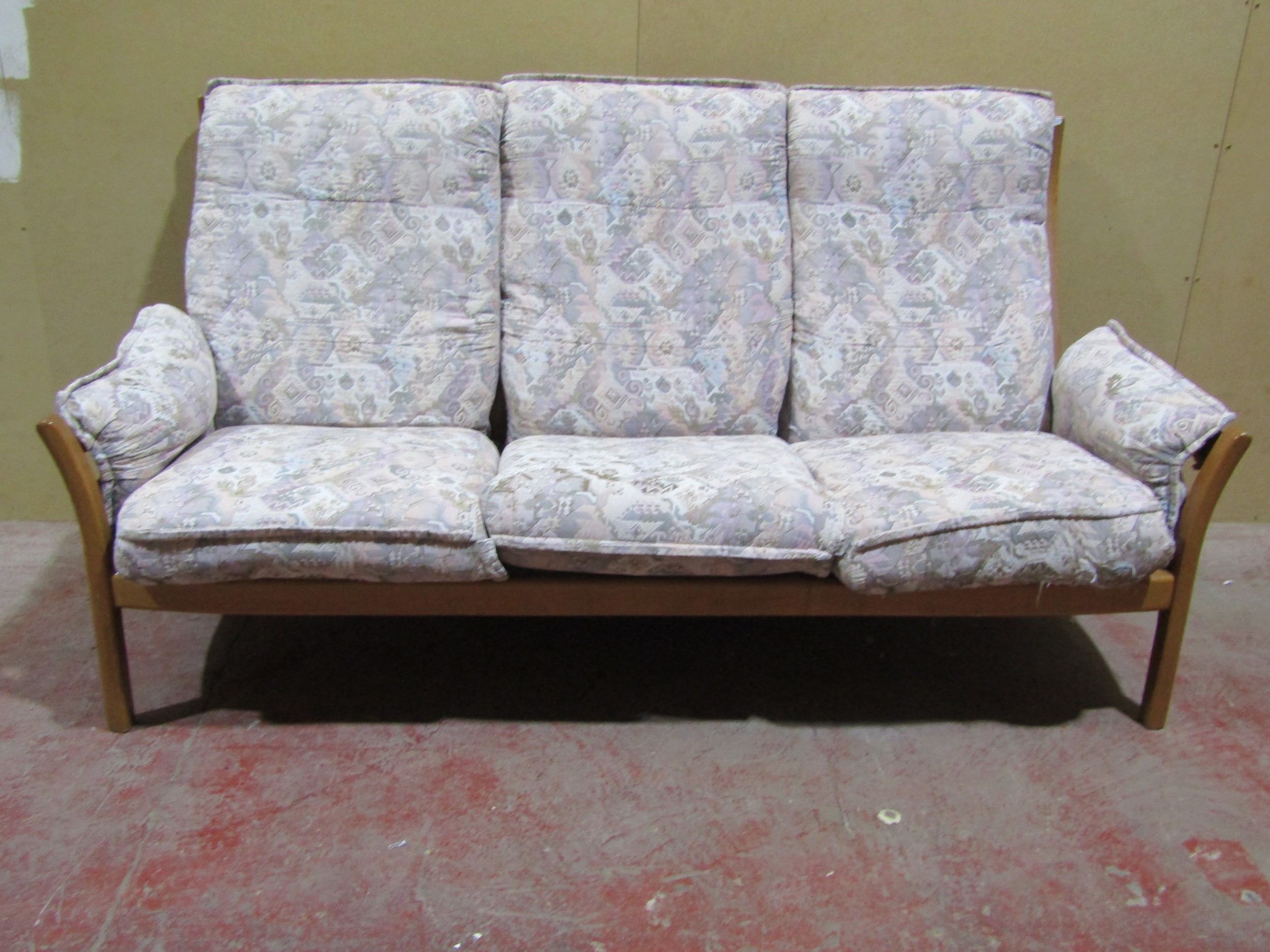 A pale Ercol three seat sofa with a pale coloured upholstery and blonde wood frame