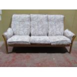 A pale Ercol three seat sofa with a pale coloured upholstery and blonde wood frame