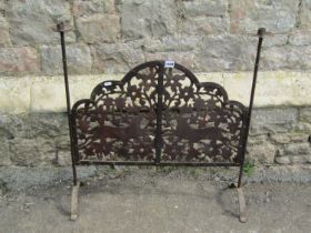 An arts and crafts style fire screen with fretted detail showing running foxes, with candle sconce