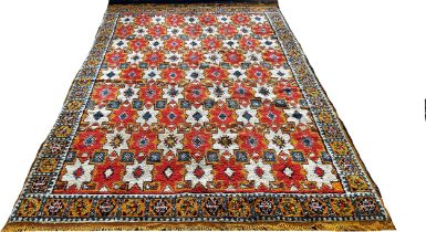 A Moroccan wool carpet with cream stars on a predominantly orange ground, 280 x 190cm approximately.