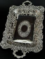 An Edwardian rectangular silver fruit dish with pierced floral sides, raised on a rectangular