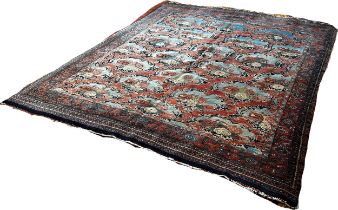 An Old Persian carpet with a repeating floral pattern on a pink ground, one corner badly worn with