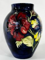 A Moorcroft Hibiscus pattern vase upon a blue ground, 17 cm