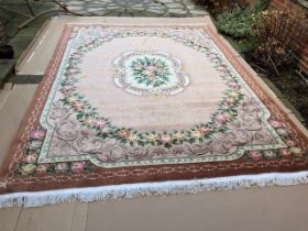 A Chinese thick pile wool carpet with a central floral medallion on a faded pink ground with a