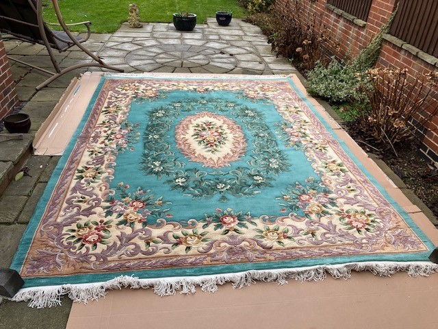 A Chinese thick pile wool carpet with a central floral bouquet with a surround of flowers on a green