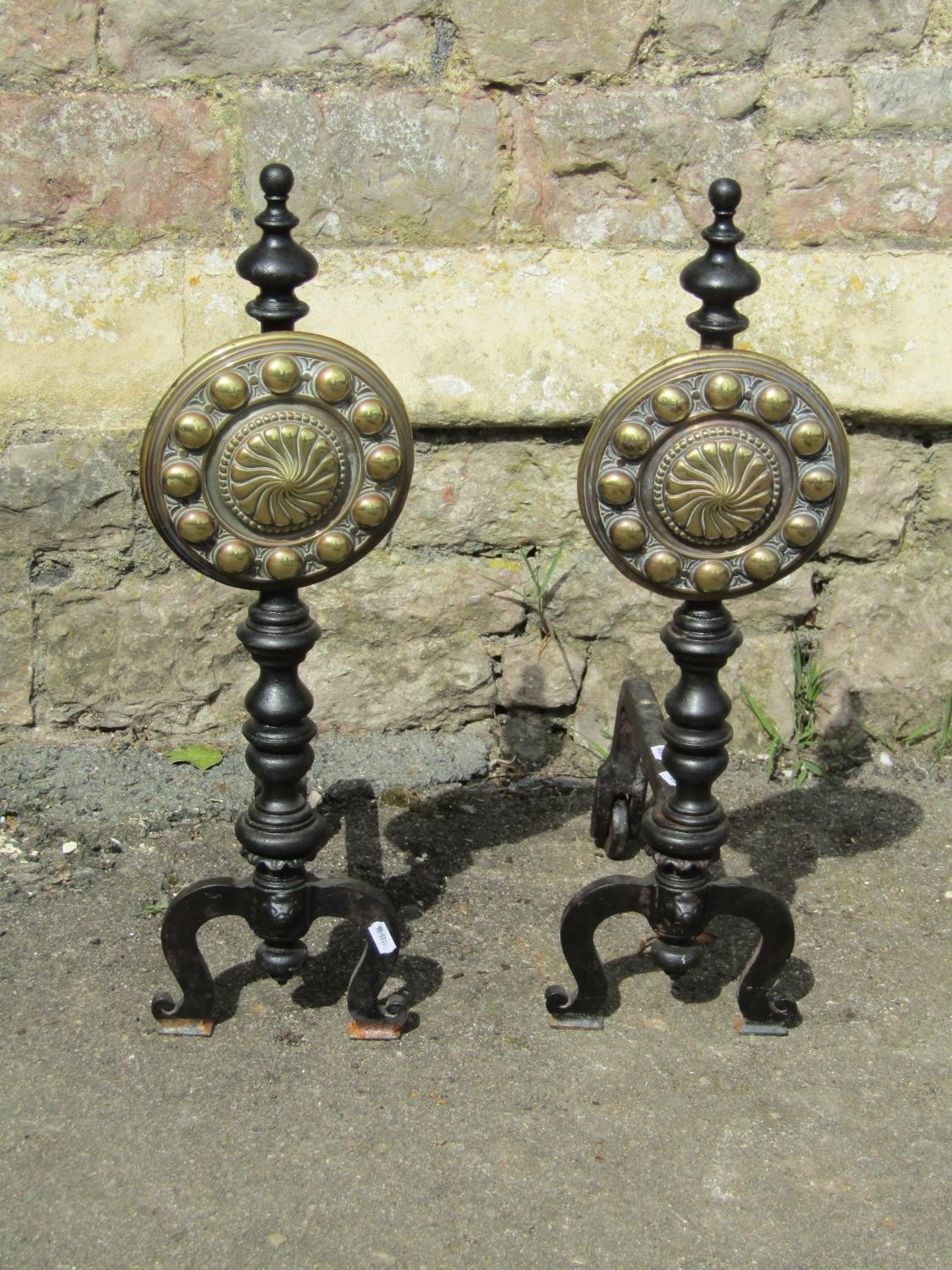 A large pair of country house iron fire dogs with cast brass panels of adjustable height with