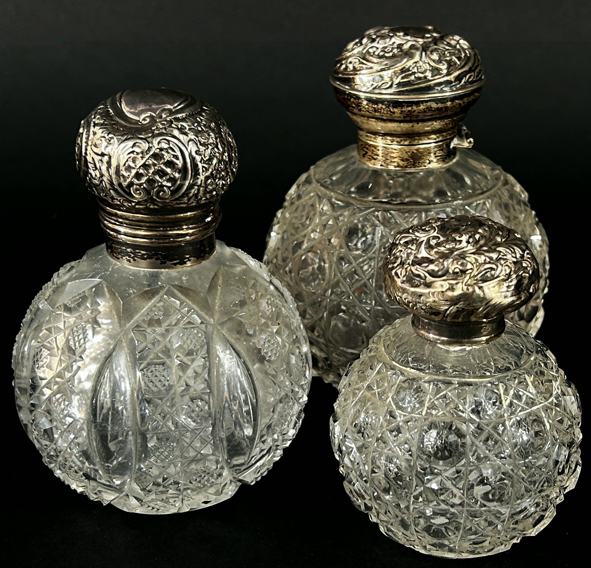 Three 19th century cut glass perfume bottles all with silver caps