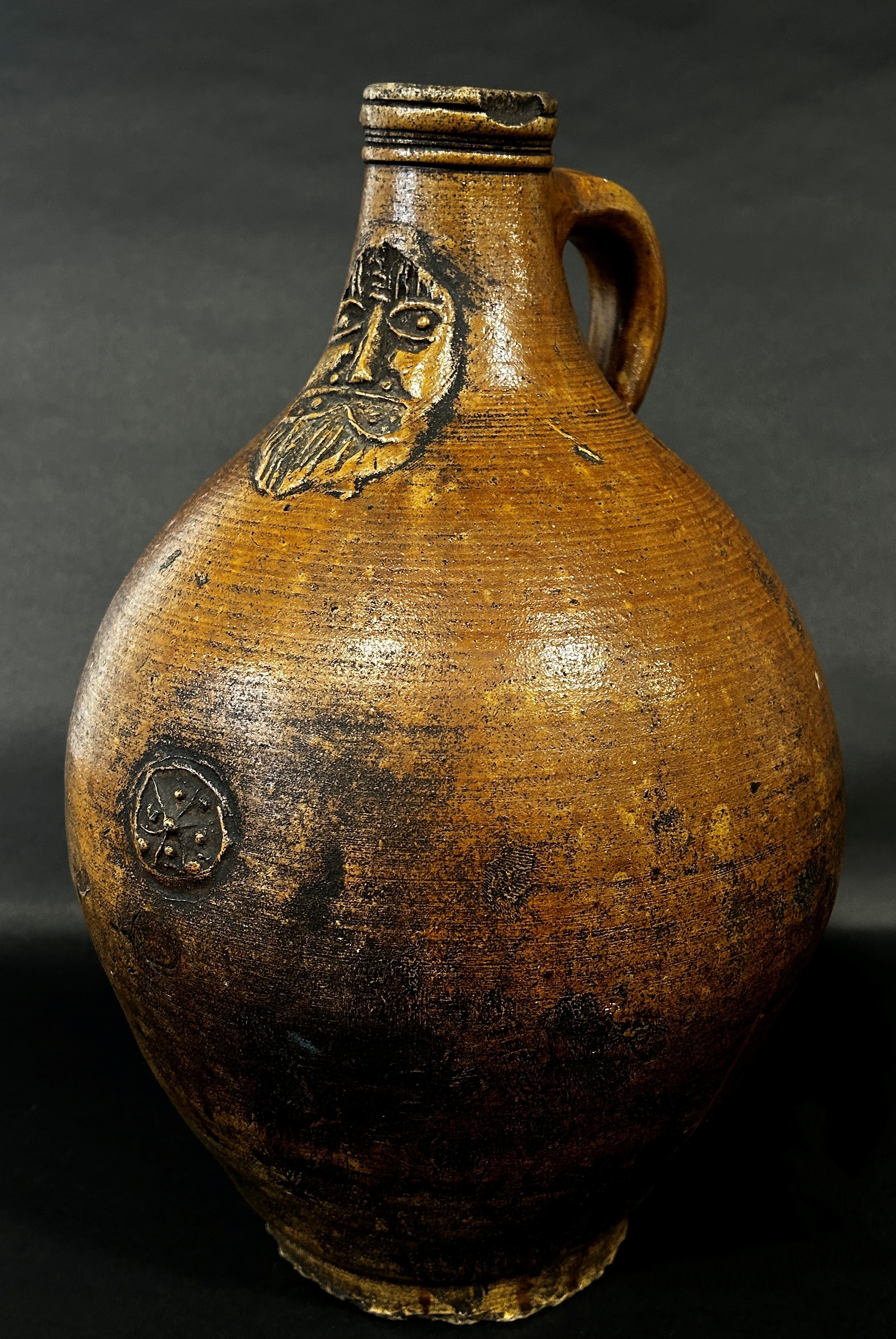 A stoneware Bellarmine with moulded face and symbol, 37cm high
