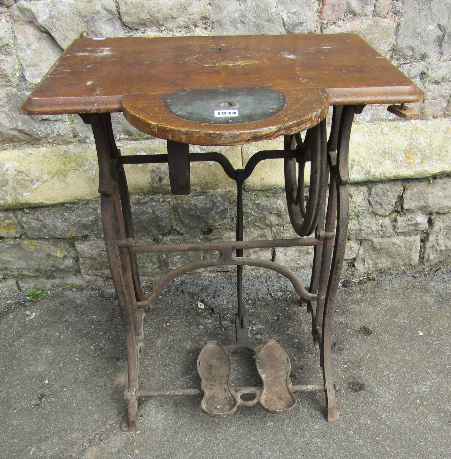 A vintage cast iron treadle sewing machine base with scumbled wooden top