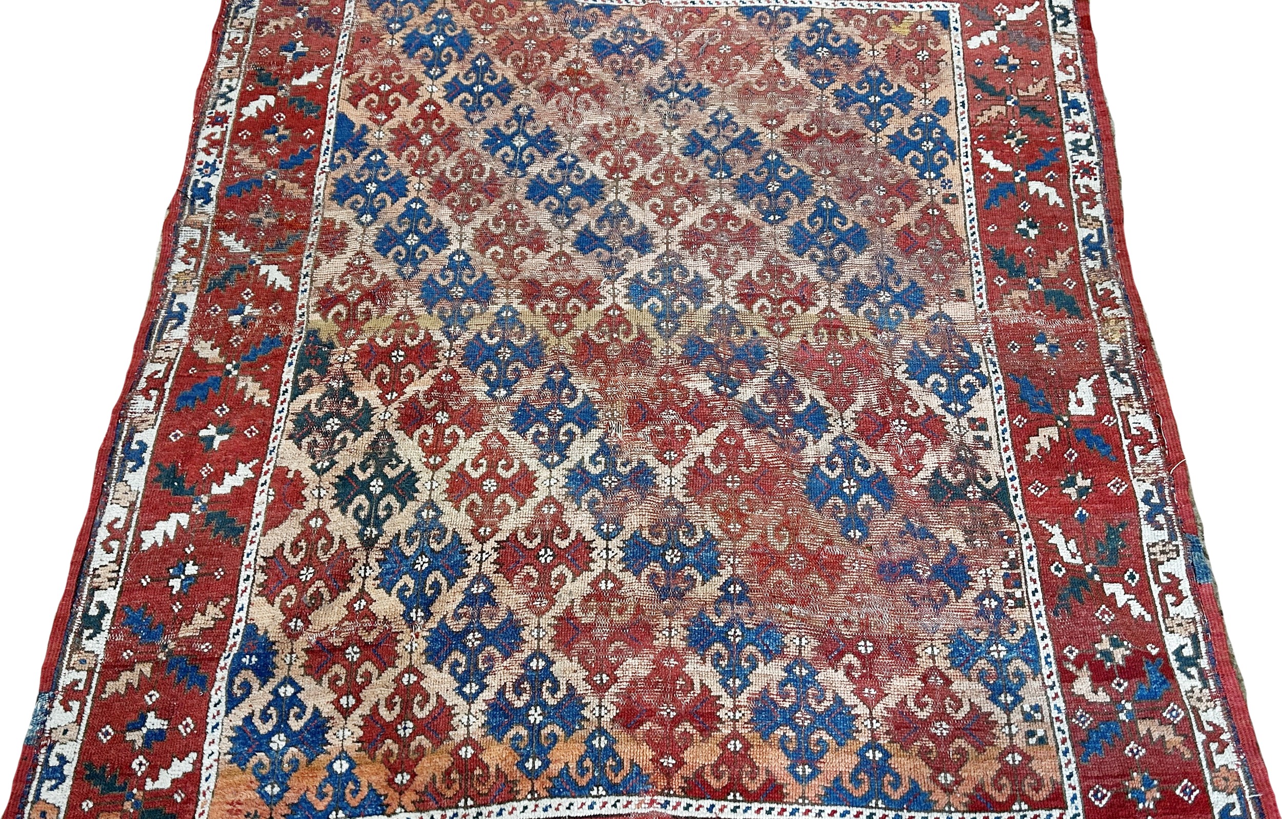 An old Persian rug with diagonal red and blue geometric patterns, worn in places, 163cm x 136cm - Image 2 of 3