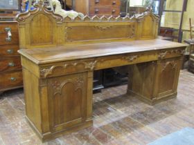 A Victorian oak sideboard with heavy Gothic influence, the base enclosed by two cupboards and