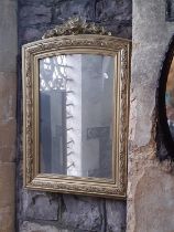 A late 19th century gilt framed mirror with arched outline and repeating lily of the valley borders,