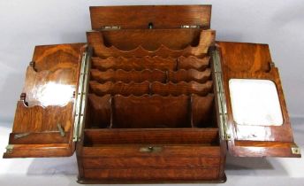 An Edwardian oak stationary cabinet with hinged doors opening to a letter rack and writing tablet to