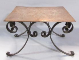 An early 20th century Arts & Crafts floral copper kettle stand with a scrolled wrought iron base,