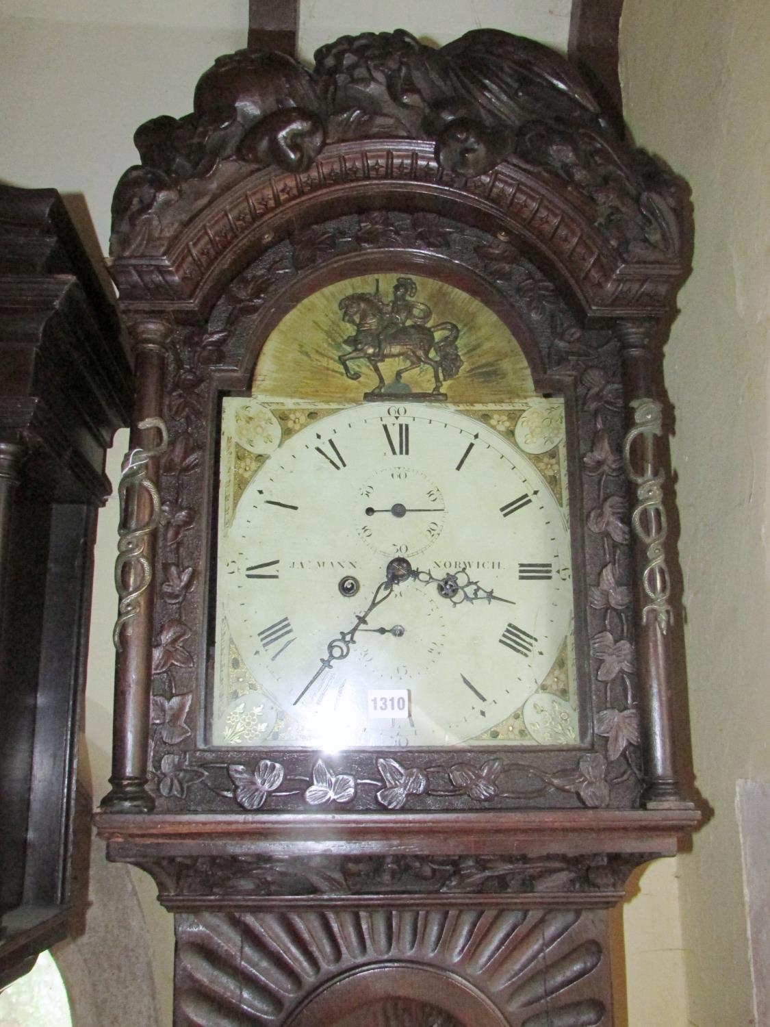 A 19th century oak longcase clock with heavy estate carving, the trunk detailing a knight fighting