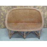 A vintage wicker two seat sofa, a mid century wicker plate glass occasional table of circular form