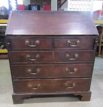 A Georgian mahogany bureau enclosing a fitted interior over two short and three long graduated