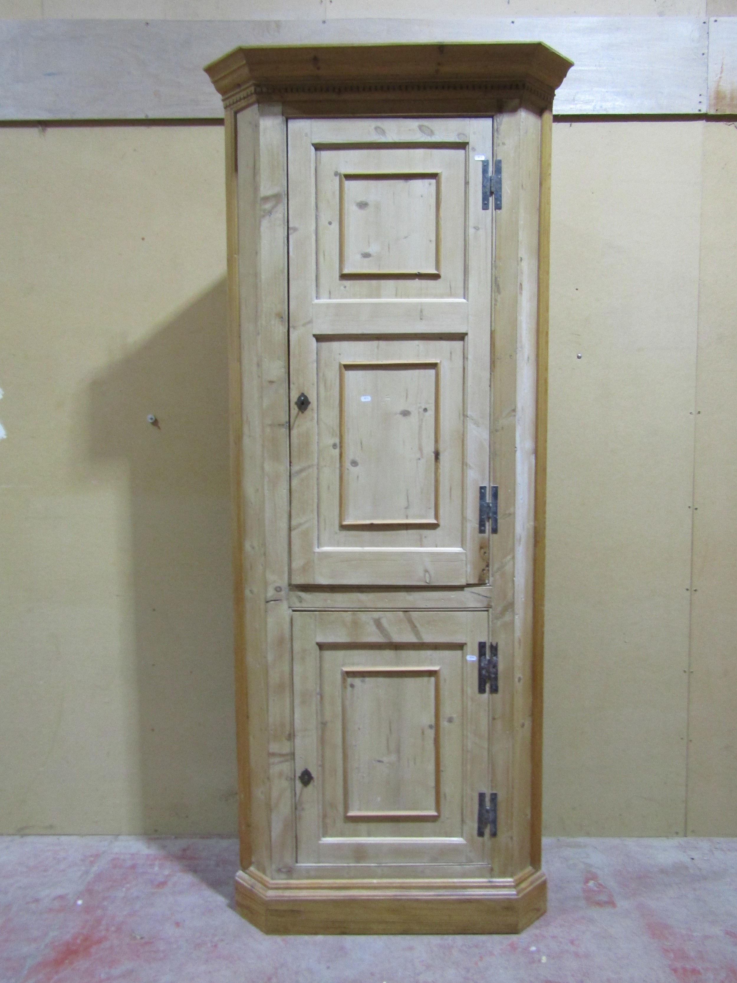 A Georgian stripped and waxed pine freestanding kitchen corner cupboard enclosed by two panelled