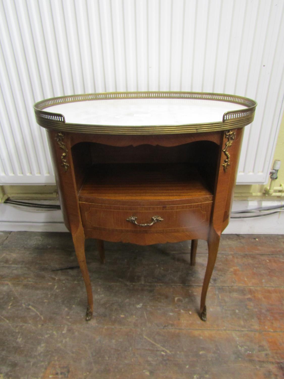 A French 18th century style oval top bedside table with open centre over a single drawer beneath a