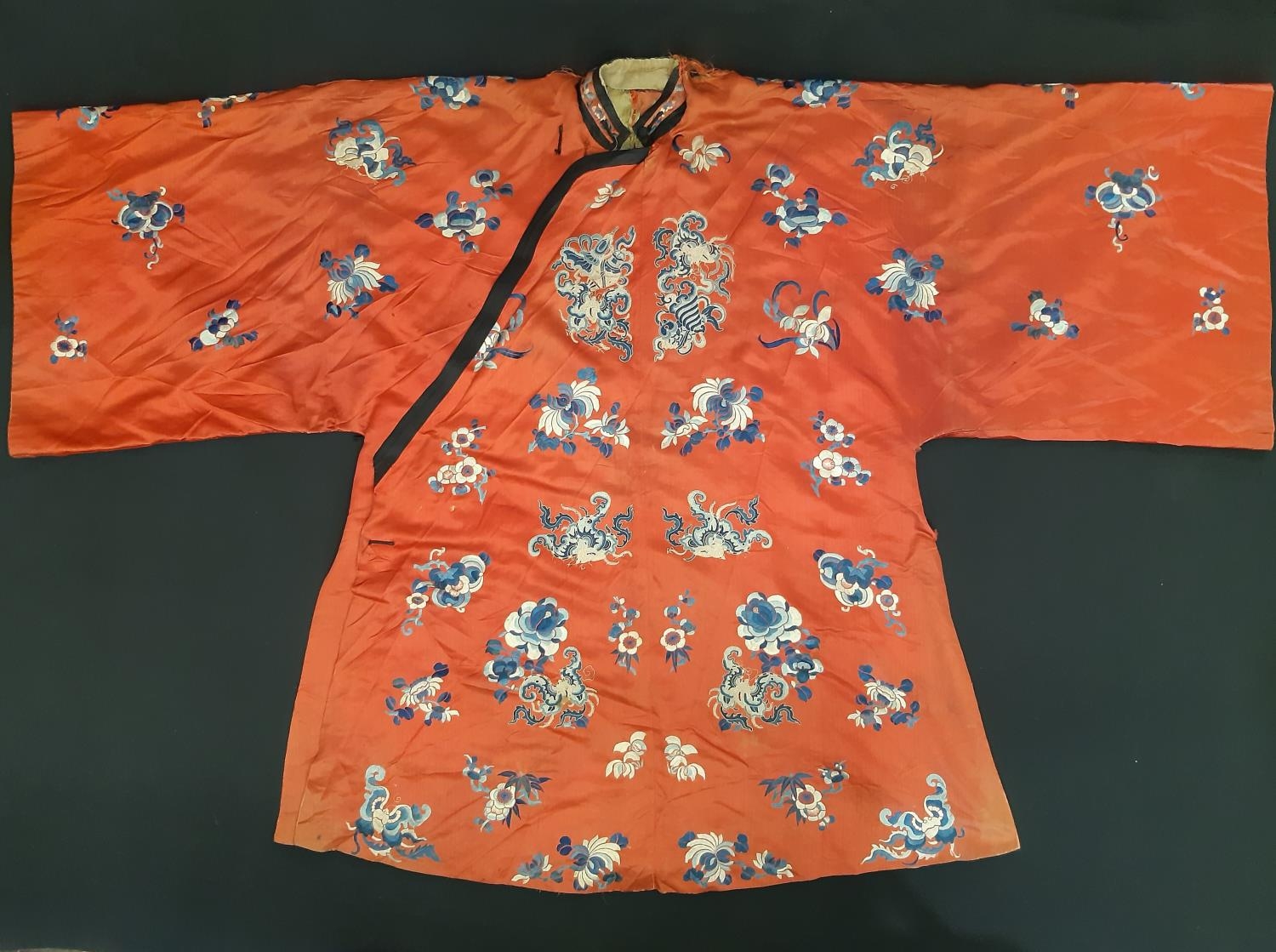 A late 19th/ early 20th century Chinese robe of red silk embroidered with flowers, moths and other