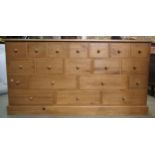 A traditional pine cabinet containing a series of 19 drawers, 180cm long x 93cm high x 48cm deep