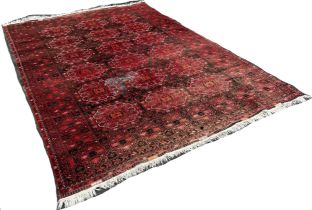 A large Afghan wool rug with a central panel design on a predominantly red ground,285 x 205cm