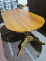 A contemporary pine kitchen table, the oval top raised on a stretcher base with central rail,