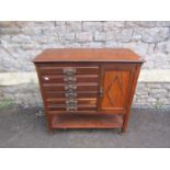 An Edwardian mahogany music cabinet enclosed by a series of 6 drawers and a side door