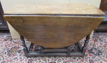 An 18th century oak and fruitwood gateleg table enclosing a single frieze drawer on turned supports,