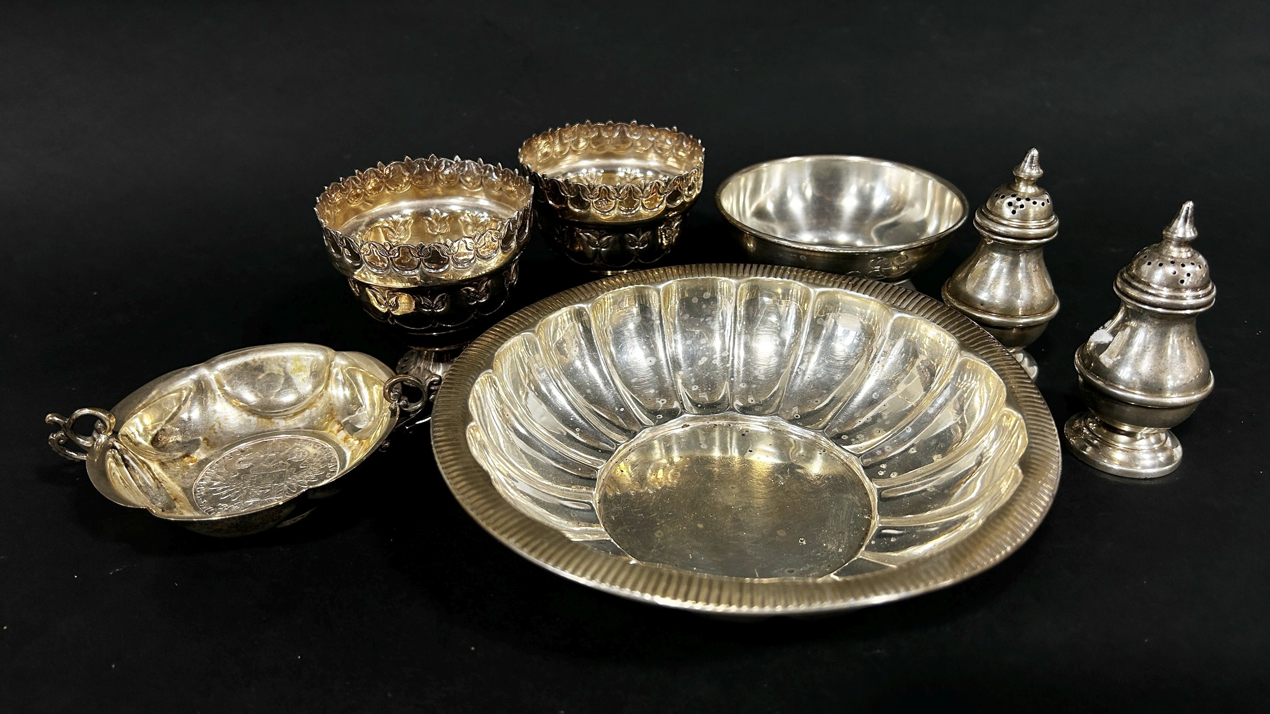 A mixed selection of silver including a pair of pepper pots, a salt cauldron, a shallow scalloped