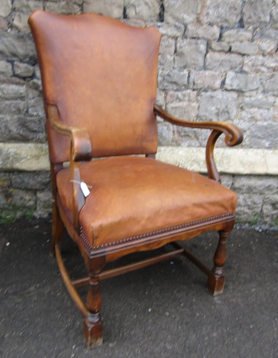 An open armchair in the Georgian style with tan coloured hide upholstered seat and back