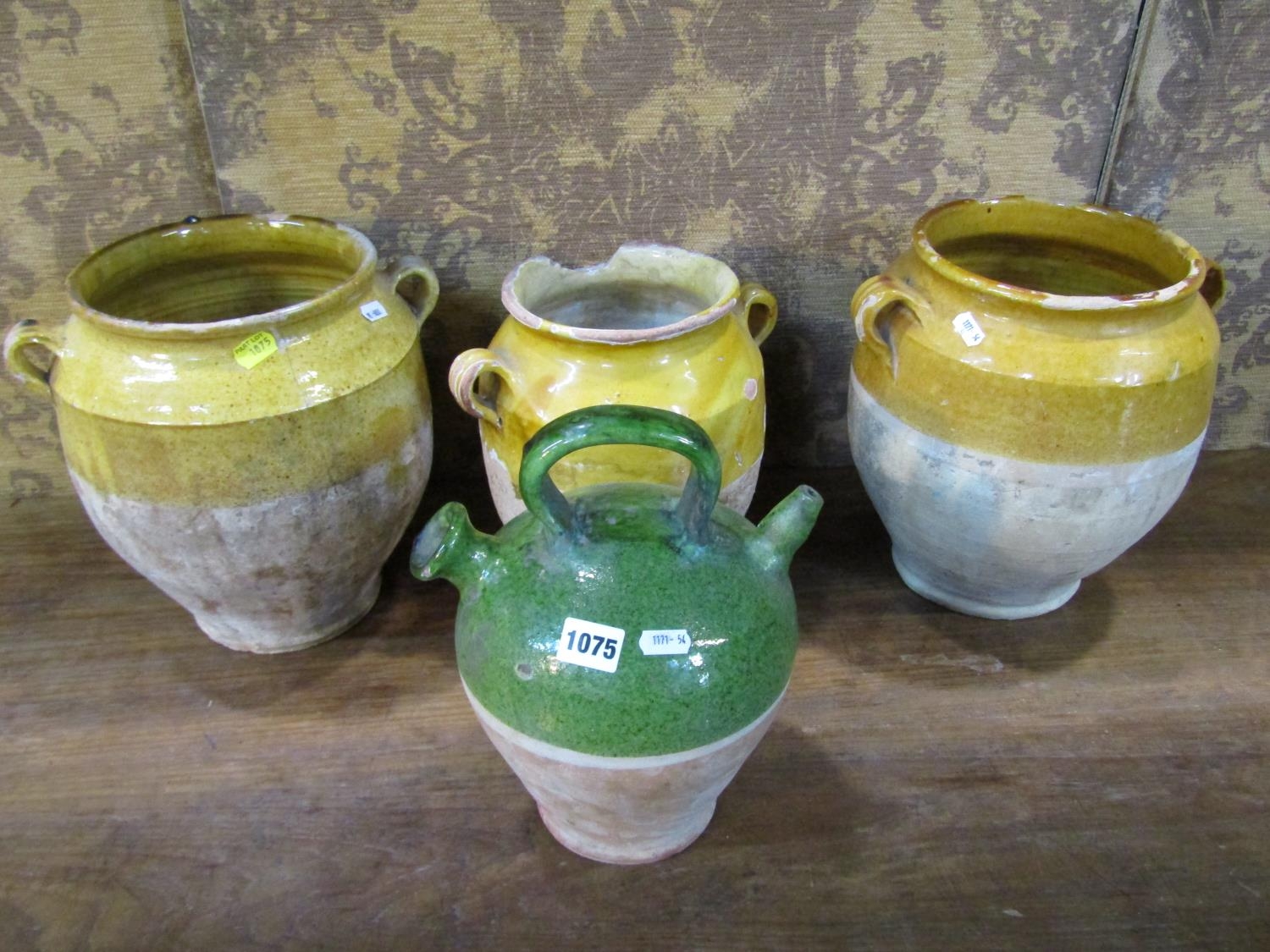 Three rustic terracotta pots with loop handles, partially glazed and a further terracotta ewer