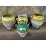 Three rustic terracotta pots with loop handles, partially glazed and a further terracotta ewer