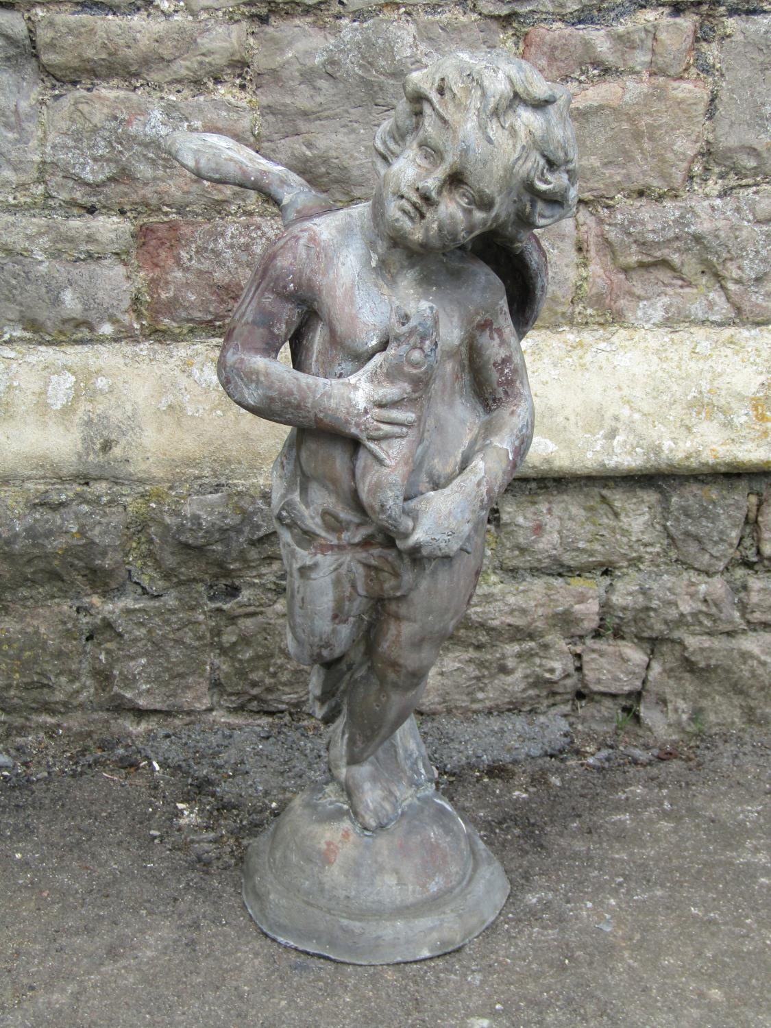 A 19th century lead water fountain in the form of a winged cherub clasping a fish, 80cm high