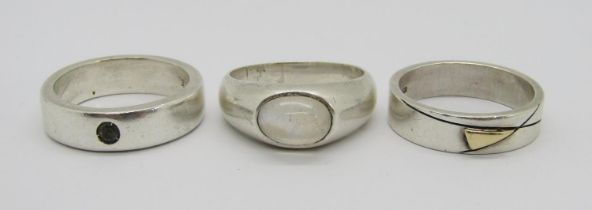 Three silver rings comprising a cabochon moonstone example, size V/W, a stylised example with yellow