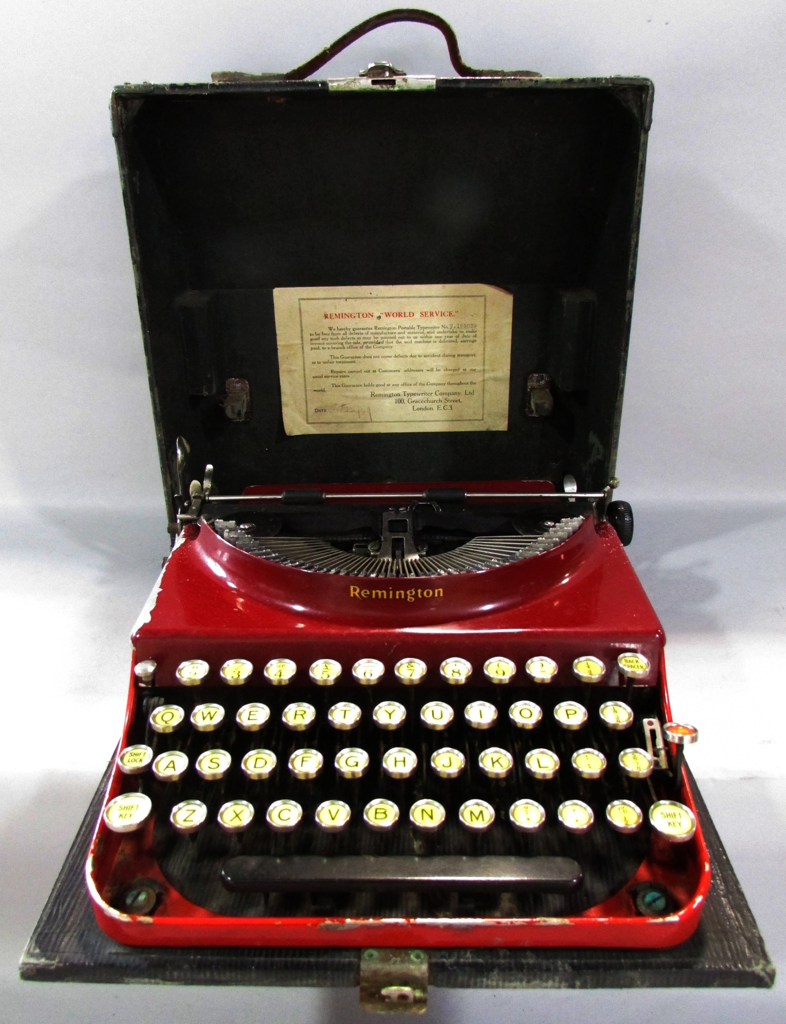 A Remington red painted “World Service” portable typewriter Serial number V.195039, in its carry