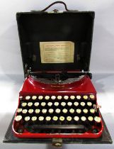 A Remington red painted “World Service” portable typewriter Serial number V.195039, in its carry