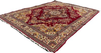 A large machine made Persian type carpet with a broad central floral medallion and scrolling flowers