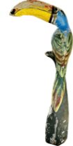 A painted carved wood Toucan perched on a frond, 100cm tall.