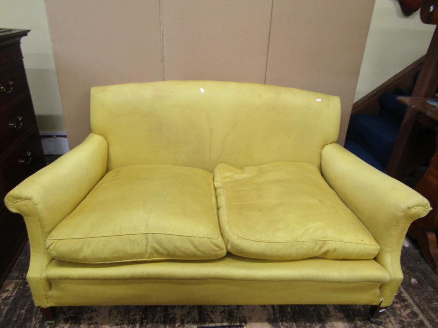 A Howard & Son two seat sofa with scrolled arms raised on square taper legs with brass cup