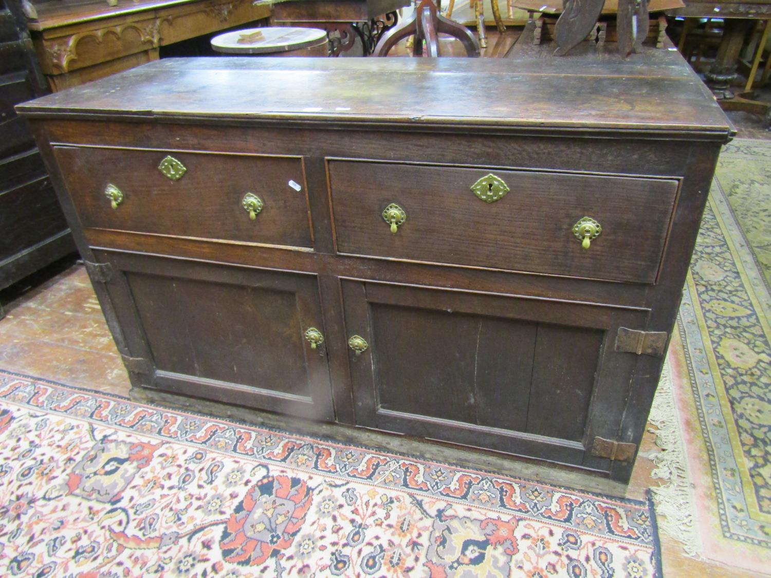 A Georgian oak dresser base with two frieze drawers and two panelled doors, with iron butterfly