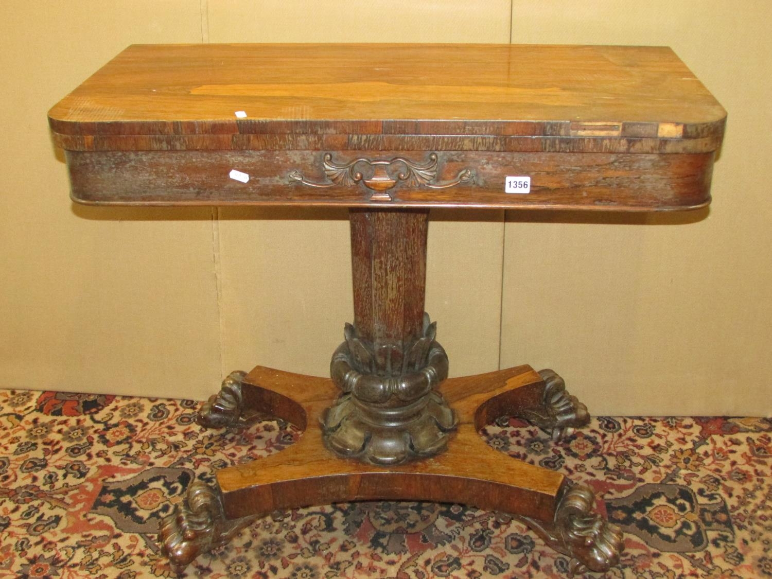 A Regency rose wood fold over top card table raised on an octagonal pillar with foliate column,