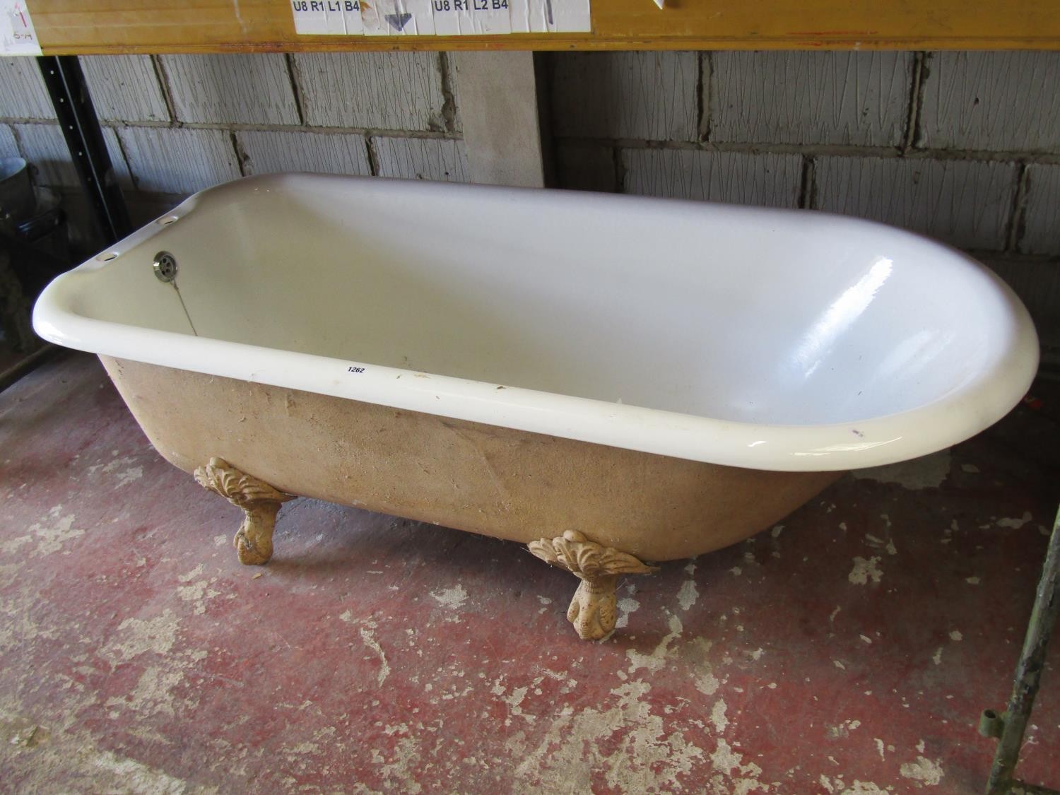 A reclaimed cast iron and enamel roll top bath tub raised on claw and ball feet together with a pair