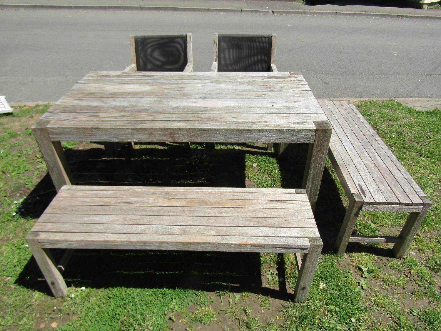 A weathered Panama Collection teak garden table of rectangular form with boarded top raised on