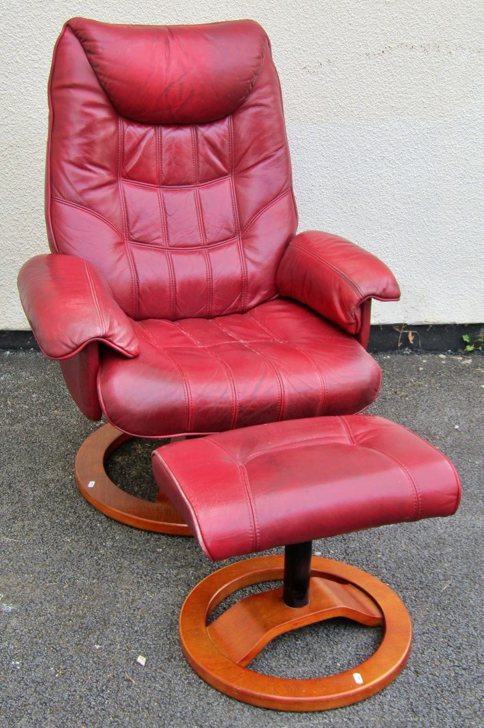 A Stressless style chair and stool in red upholstery