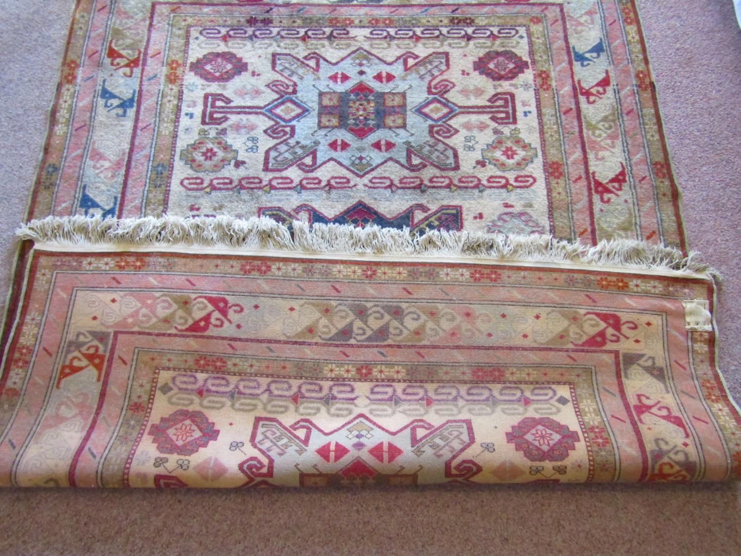 A wool rug in the eastern manner with triple medallion upon a pale cream field, within running - Image 4 of 4